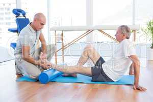 Trainer working with man on exercise mat