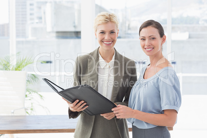 Smiling businesswomen looking at camera and working together