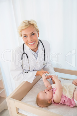 Portrait blonde doctor and baby girl taking a temperature