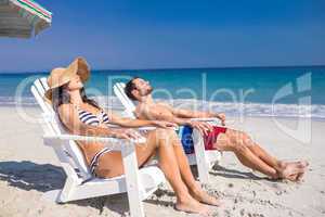 Happy couple relaxing on deck chair at the beach