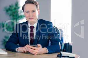 Confident businessman with smartphone looking at camera