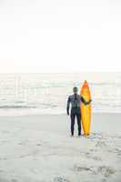 Man in wetsuit with a surfboard on a sunny day