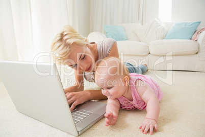 Happy blonde mother with her baby girl using laptop