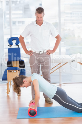 Trainer working with woman on exercise mat