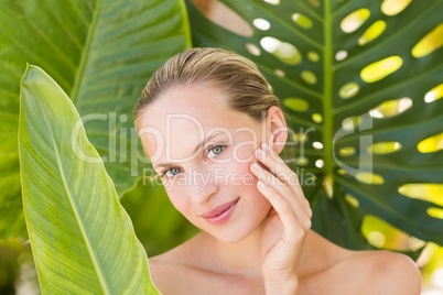 Beautiful blonde smiling at camera behind leaf