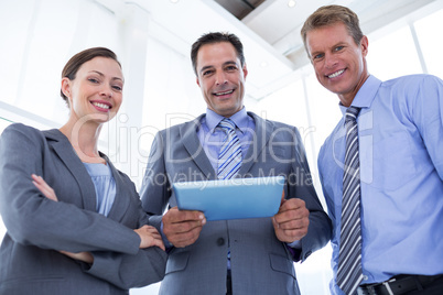 Business colleagues smiling at camera and holding tablet