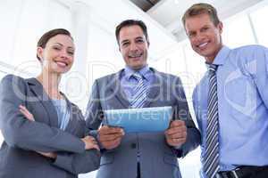 Business colleagues smiling at camera and holding tablet