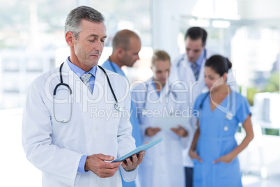 Doctor looking at clipboard while his colleague discussing