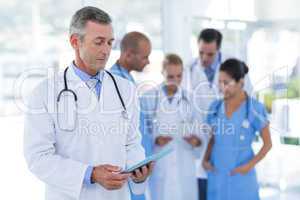 Doctor looking at clipboard while his colleague discussing