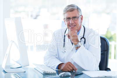 Smiling doctor working on computer at his desk