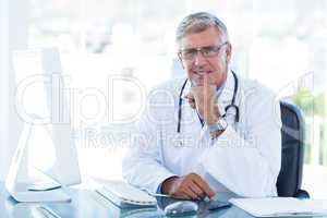 Smiling doctor working on computer at his desk