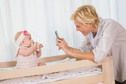 Happy mother taking a picture of her baby girl