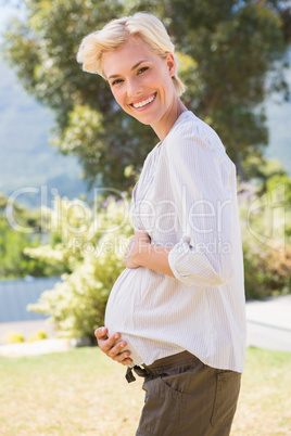 Portrait smiling blonde pregnant hand on hid belly