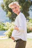 Portrait smiling blonde pregnant hand on hid belly