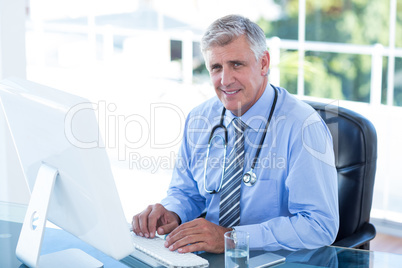 Smiling doctor working on computer at his desk