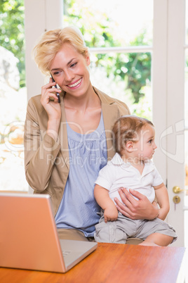 Blonde woman with his son using phone and laptop