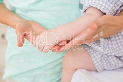 Happy mother looking at arm of her baby boy