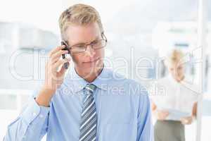 Businessman having a phone call with colleague in background