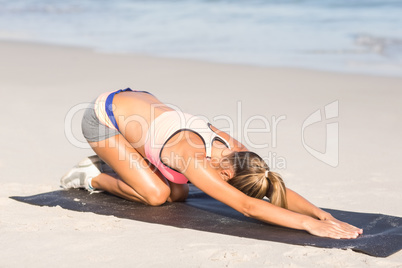 Fit woman stretching her back on exercise mat