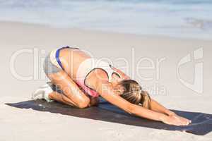 Fit woman stretching her back on exercise mat