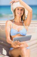 Pretty woman holding tablet pc in the hammock