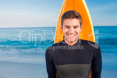 Man in wetsuit with a surfboard on a sunny day