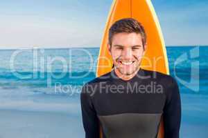 Man in wetsuit with a surfboard on a sunny day