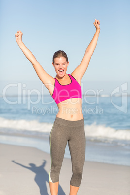 Wear view of beautiful fit woman cheering with arms rise