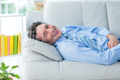 Businessman smiling at camera lying on couch