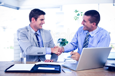 Businessmen shaking hands at desk