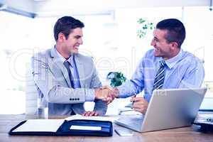 Businessmen shaking hands at desk