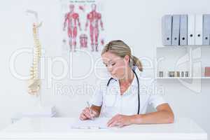 Doctor writing on clipboard at her desk