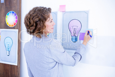 Wear view of creative businesswoman writing on post it