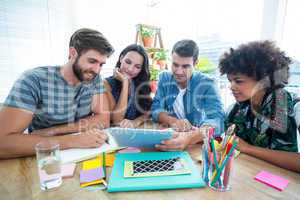 Happy creative business team using tablet in meeting