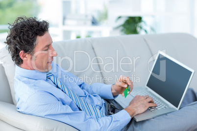 Businessman doing online shopping on couch