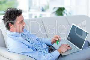 Businessman doing online shopping on couch