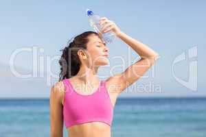 Beautiful brunette putting water bottle in her head