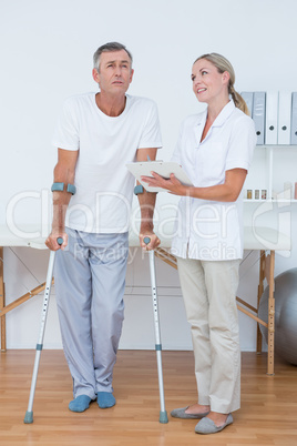 Man with crutch speaking with his doctor