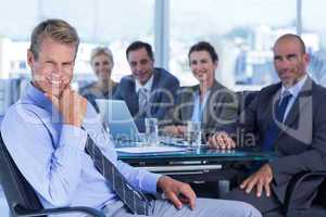 Businessman smiling at camera with colleagues behind