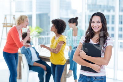 Smiling businesswoman with colleagues in background at office