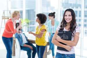 Smiling businesswoman with colleagues in background at office