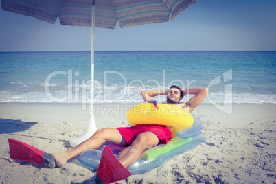 Man lying on the beach with flippers and rubber ring