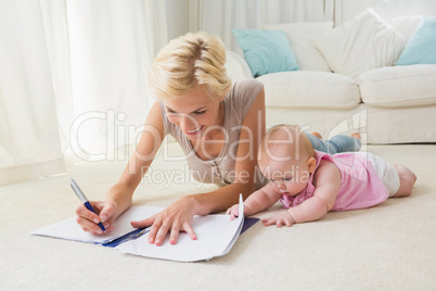 Happy blonde mother with her baby girl writting on a copybook