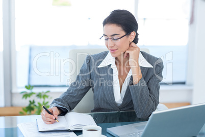 Businesswoman working with her laptop and writing notes