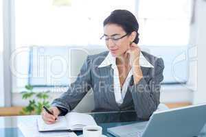 Businesswoman working with her laptop and writing notes