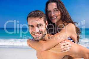 Man giving piggy back to his girlfriend at the beach