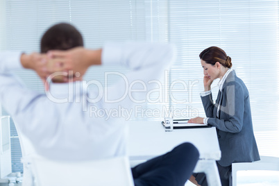 Businessman relaxing in a swivel chair while his colleague readi