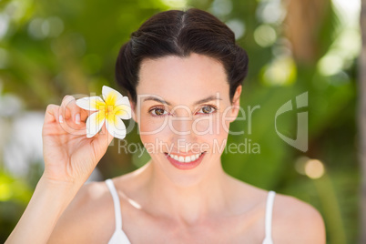 Happy brunette holding a white flower