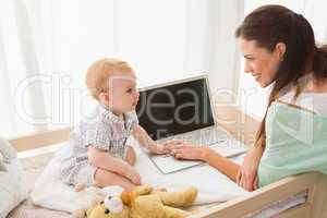 Happy mother using laptop with her baby boy