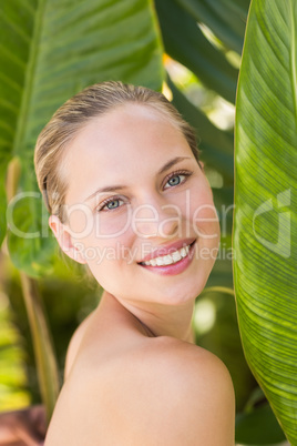 Beautiful blonde smiling at camera behind leaf